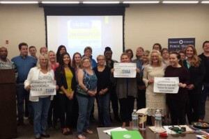 A group of people holding signs in front of a projector screen.