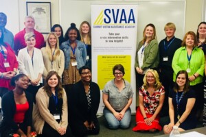 A group of people posing for a picture in front of a svaaa sign.