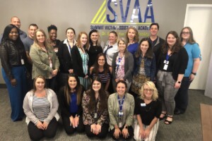 A group of people posing for a picture in front of the svaia logo.