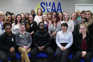 A group of people sitting in front of an asvaa sign.