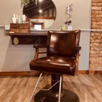 A brown chair in front of a mirror.