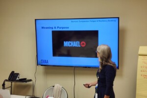 A woman standing in front of a large screen tv.